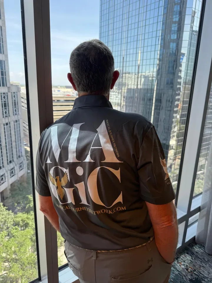 Magic at a city window, the back of his shirt reading MAGIC in large gold letters