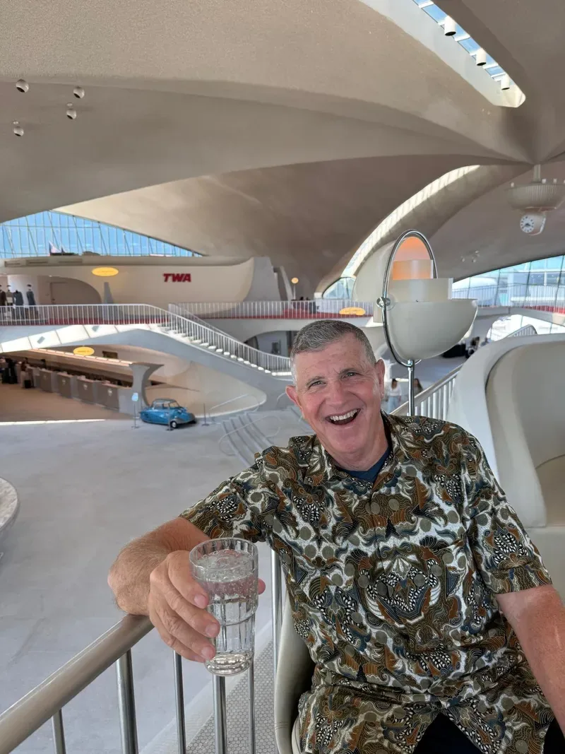 Magic smiling at an airport, raising a glass
